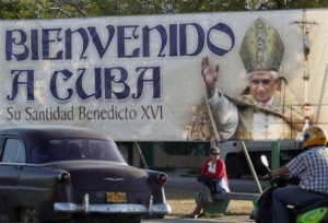 Woman sits under banner of Pope Benedict XVI in Havana